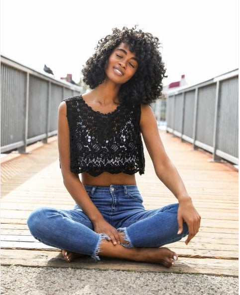 Model wearing a stylish black crop top and denim jeans representing boho chic clothing on a sunny boardwalk