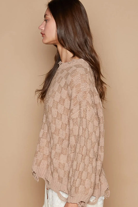 Side view of a boho checkered distressed sweater in a soft beige color with a loose fit and textured design
