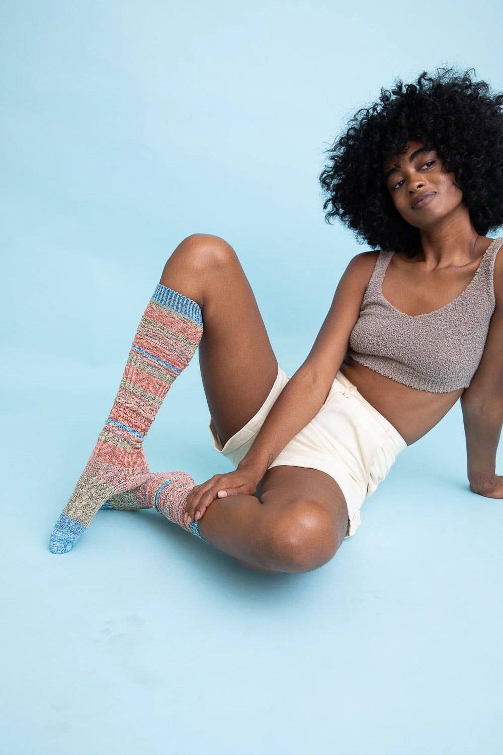 Colorful and comfortable boho socks for women displayed by a model seated on a blue background