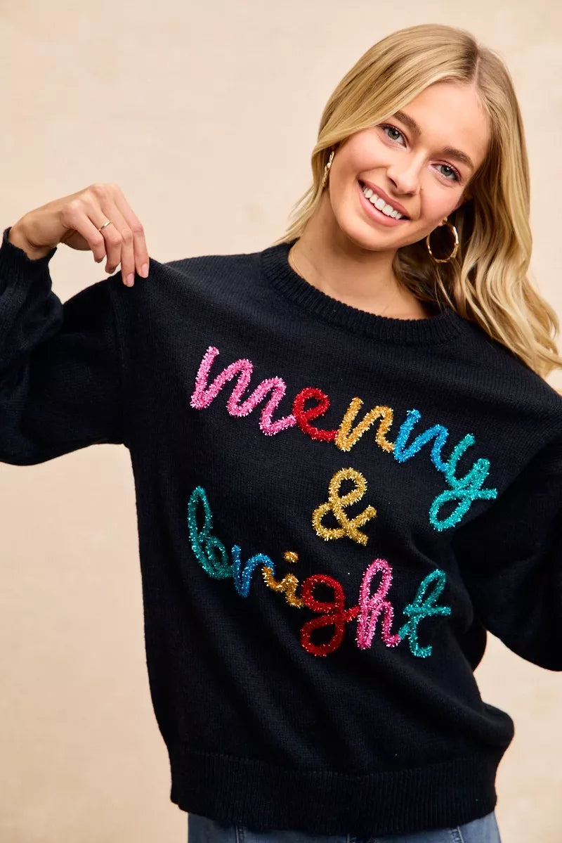 Happy woman wearing a tinsel lettering Christmas sweater with colorful 'merry & bright' design