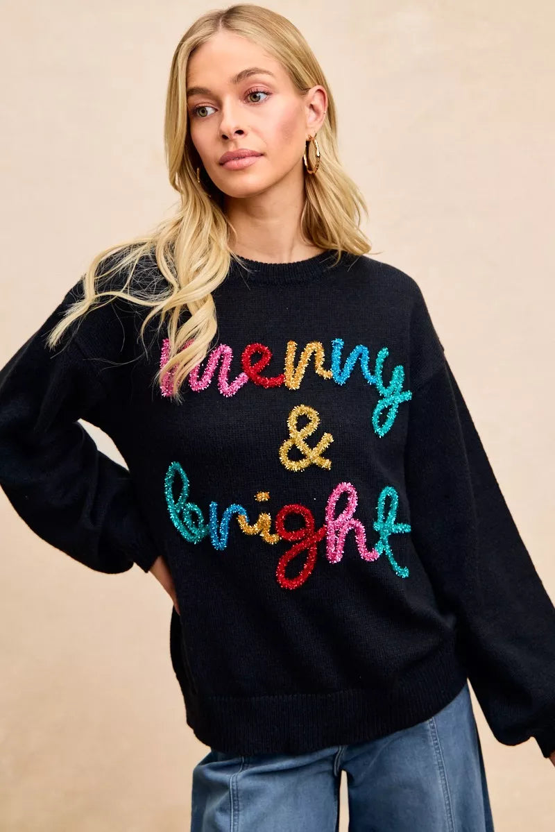 Black Christmas sweater with tinsel lettering that says merry & bright in colorful text