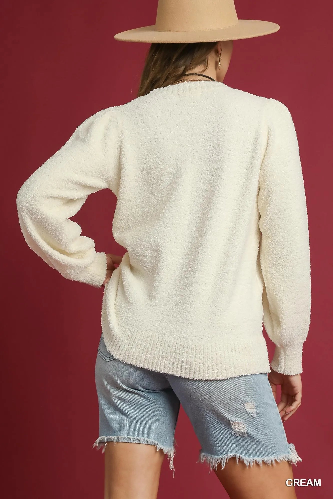 Model wearing an Umgee textured sweater in cream color, styled with denim shorts