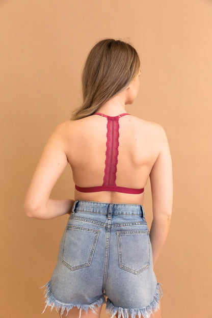 Back view of a burgundy lace t-back bralette paired with high-waisted denim shorts