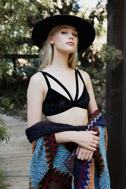 Model wearing a crushed velvet bralette with stylish straps, surrounded by nature