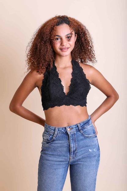 Model wearing a floral lace halter bralette styled with high-waisted denim jeans