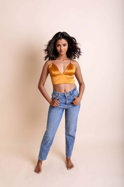 Leto Collection satin longline bralette in gold paired with high-waisted blue jeans for a stylish look