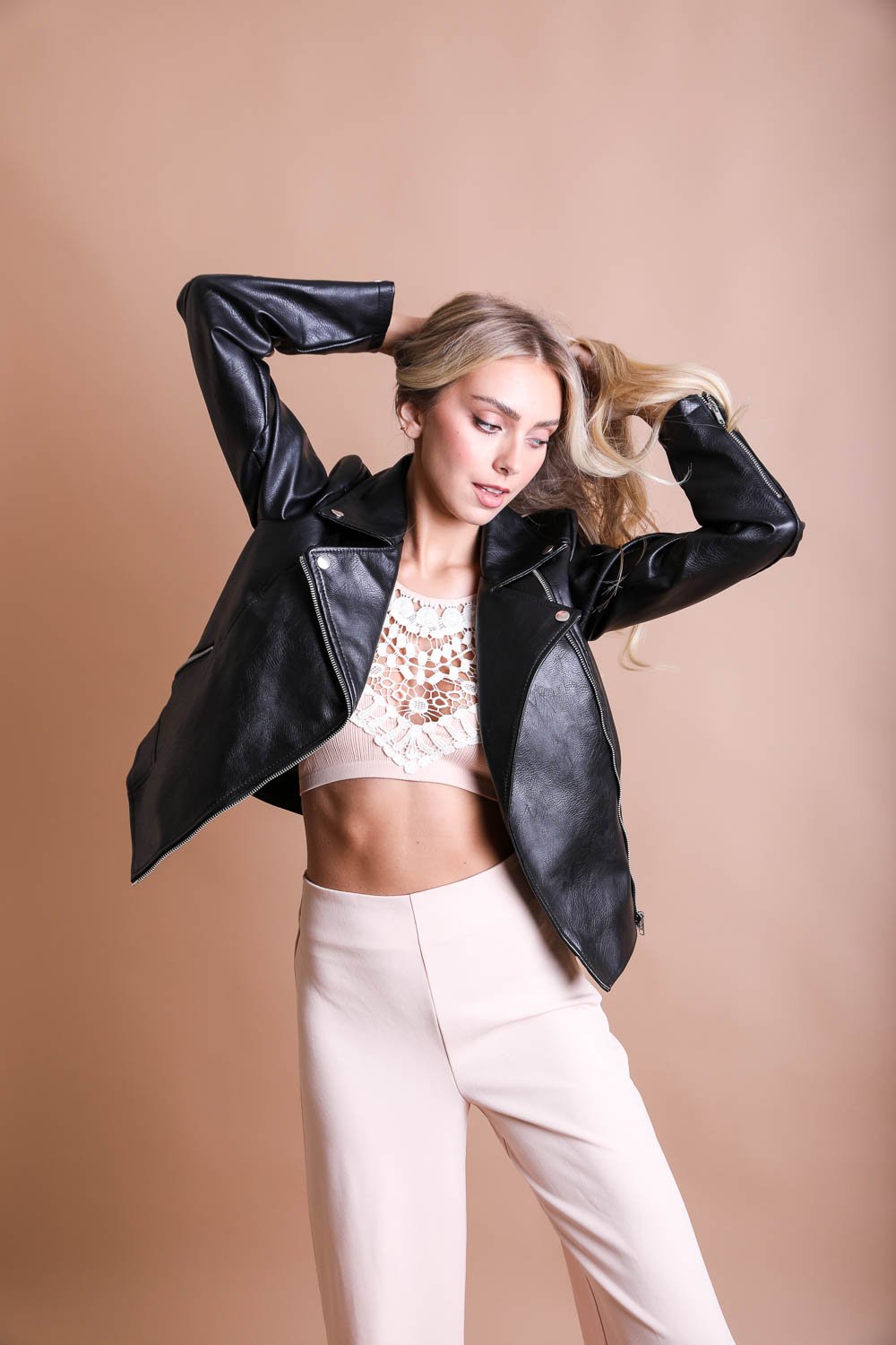 Model wearing a crochet lace high neck bralette underneath a black leather jacket for stylish layering