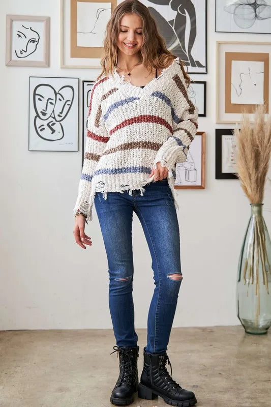 Trendsi Boho Striped Frayed Edge Sweater in natural tones paired with ripped jeans for a casual look