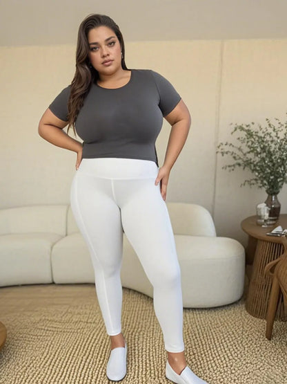 Plus size model wearing wide waistband sports leggings paired with a fitted gray top for an active lifestyle