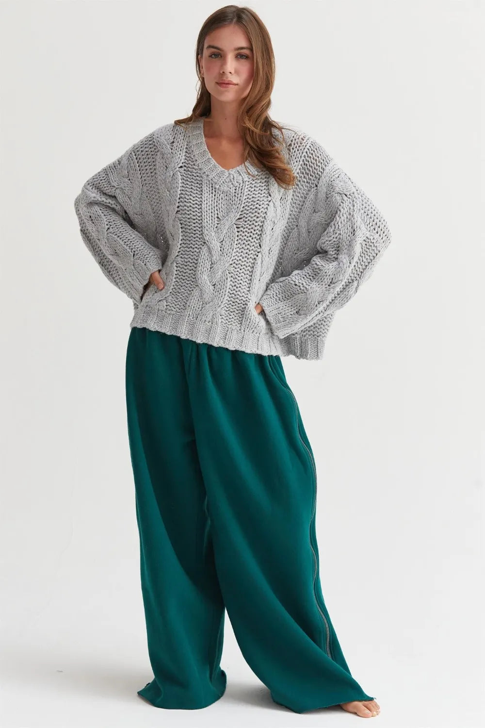 Trendy boho cable knit v-neck sweater in light gray paired with relaxed green wide-leg pants