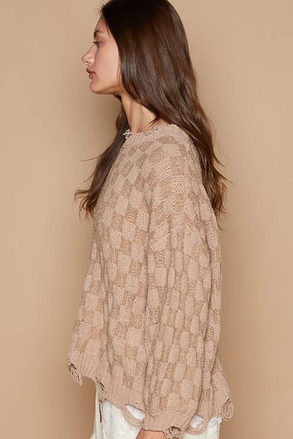 Side view of a boho checkered distressed sweater in a soft beige color with a loose fit and textured design