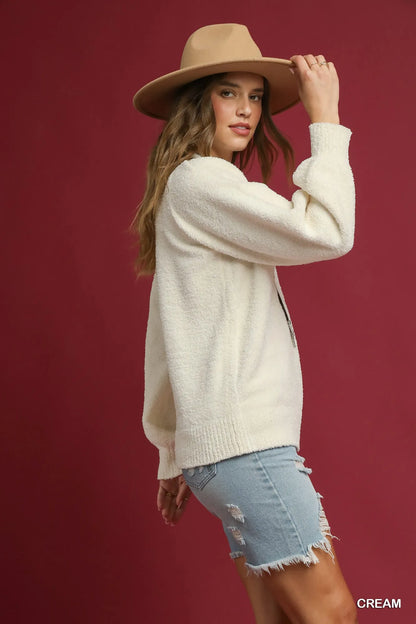 Umgee textured sweater in cream color styled with a beige hat and denim shorts