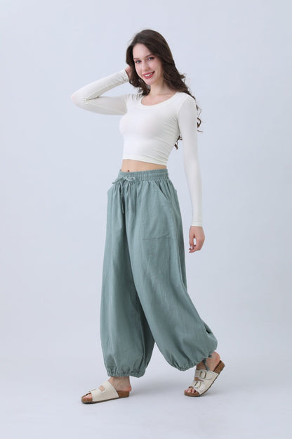 Model wearing boho linen pants for women in light green, paired with a fitted top and sandals