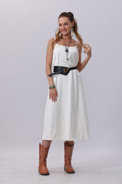 Woman in white dress wearing a stylish boho wide waist belt, paired with brown cowboy boots.