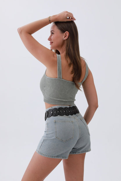 Stylish woman wearing an edgy hollow-out belt with high-waisted denim shorts and ribbed crop top
