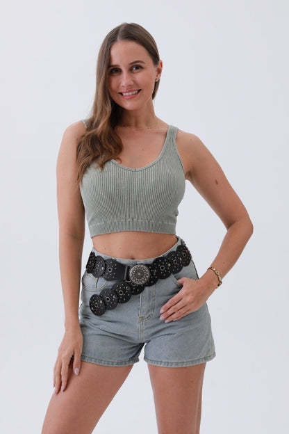 Woman wearing an edgy hollow-out belt with a stylish design, paired with a crop top and shorts