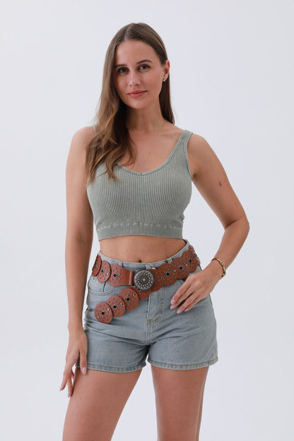 Model wearing an edgy hollow-out belt with decorative studs over a crop top and denim shorts