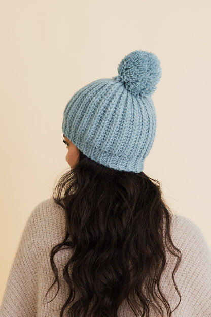 Light blue chunky cable knit pom beanie with a fluffy pom-pom for stylish winter wear