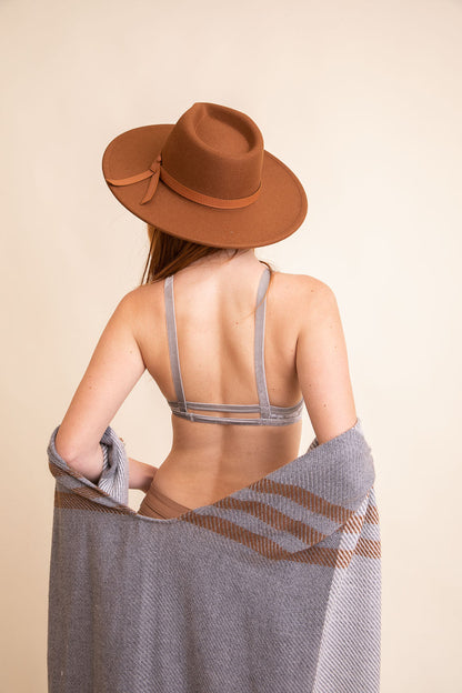 Back view of a model wearing a crushed velvet bralette from Leto Collection with a stylish hat and shawl