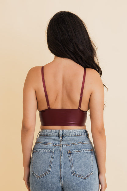 Back view of a burgundy vegan leather bralette with adjustable straps paired with high-waisted jeans