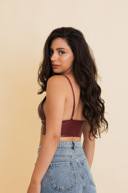 Model wearing a maroon vegan leather bralette paired with high-waisted jeans