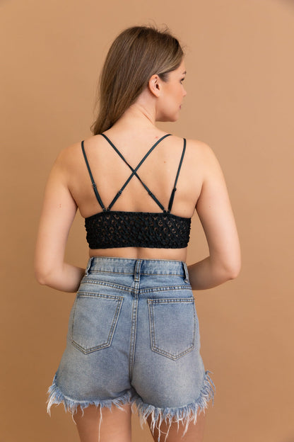 Back view of a woman wearing a boho crochet lace bralette with crisscross straps and high-waisted shorts