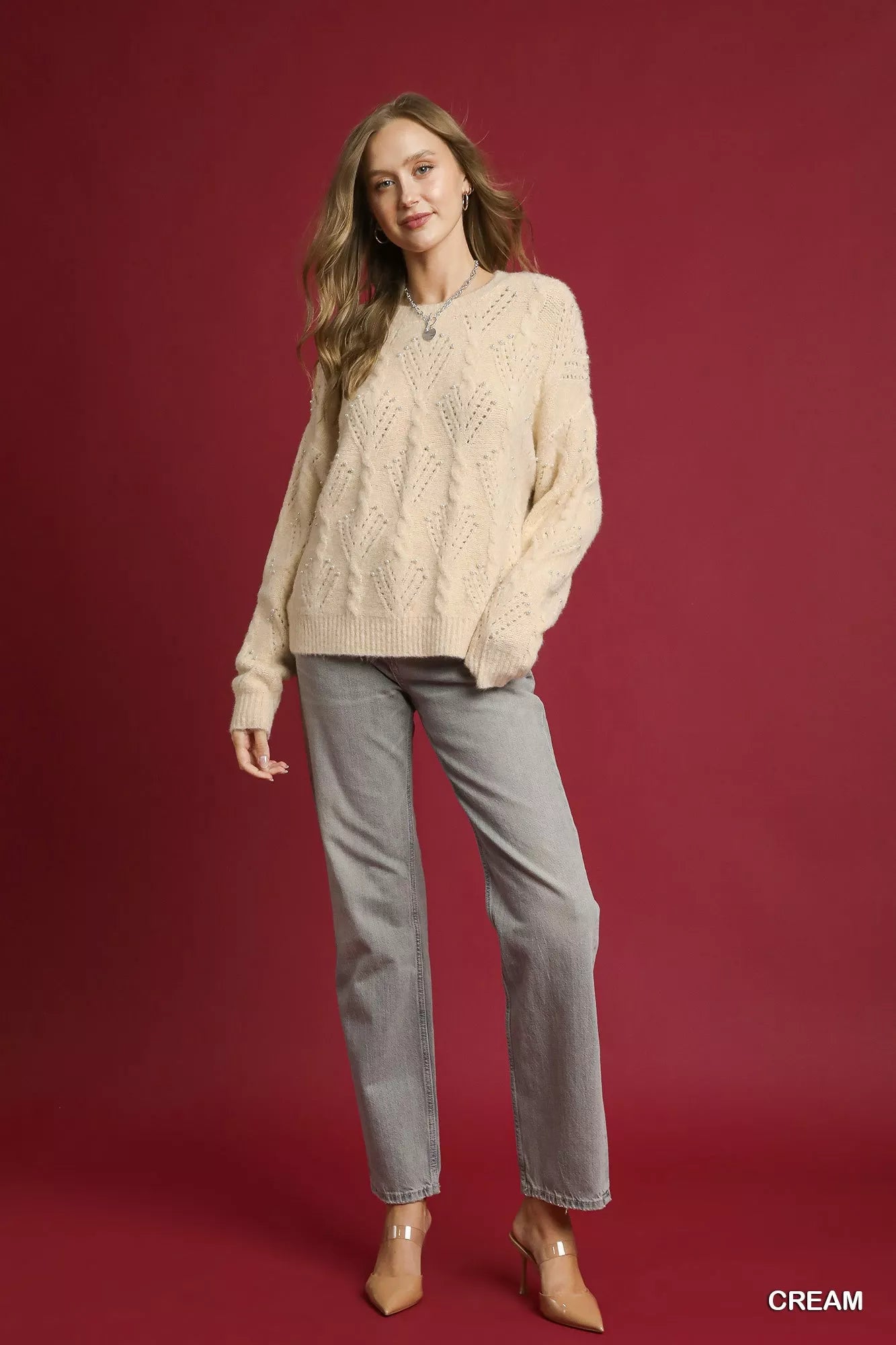 Cream pearl embellished long sleeve sweater with a textured design, paired with gray jeans for a stylish look