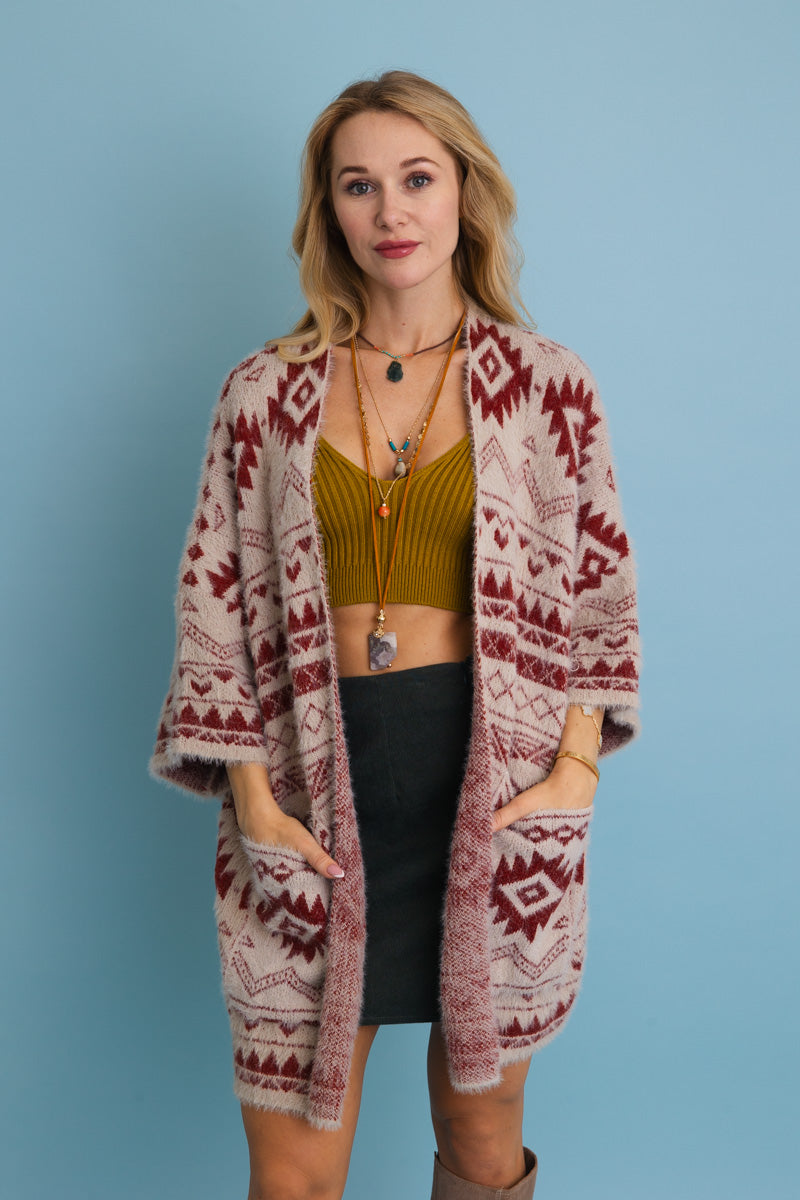 Model wearing an Aztec print knit cardigan with pockets over a green top and black skirt