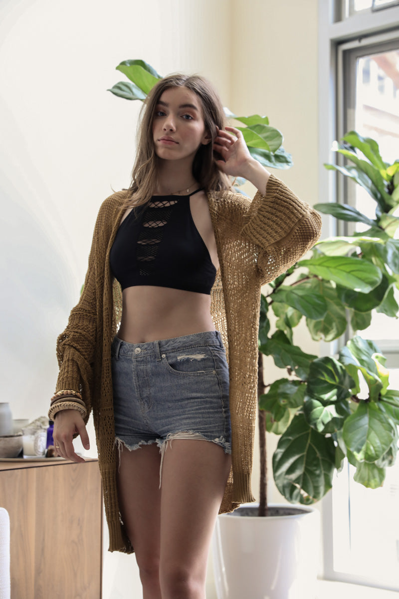 Leto Collection boho knit netted cardigan in mustard worn over a black crop top and denim shorts