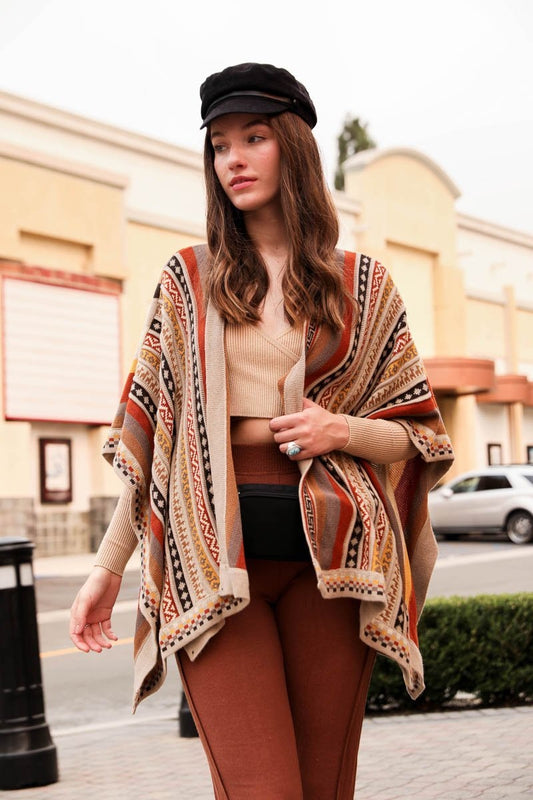 Leto Collection boho ruana wrap in colorful tribal pattern, stylishly worn over a beige top and brown leggings