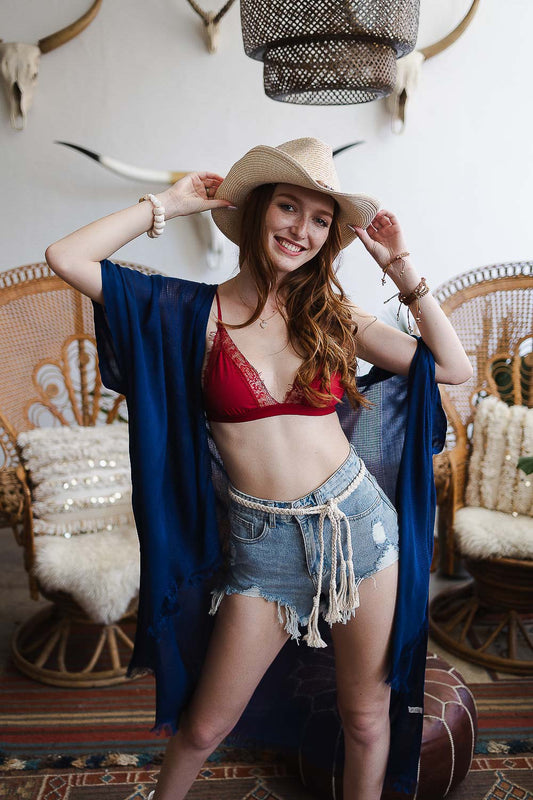 Woman in a stylish boho outfit featuring a blue kimono and denim shorts, showcasing a boho braided rope belt.