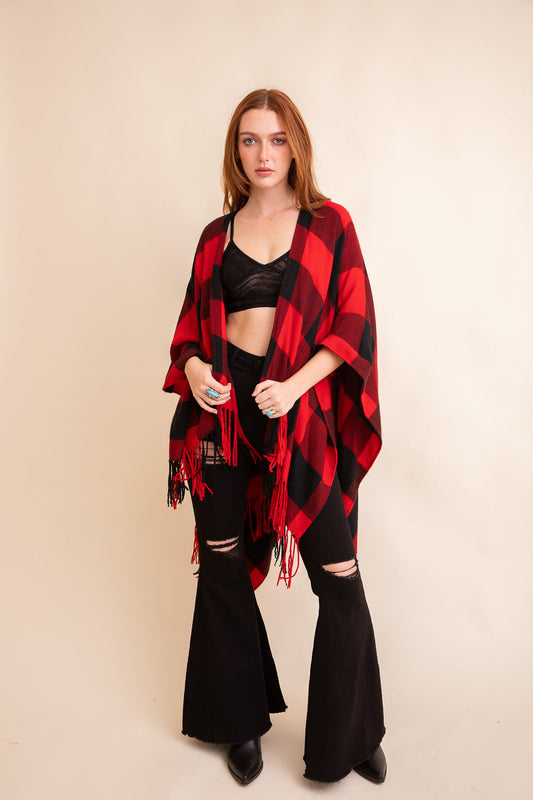 Red and black buffalo check tassel ruana wrapped around a model with a stylish outfit