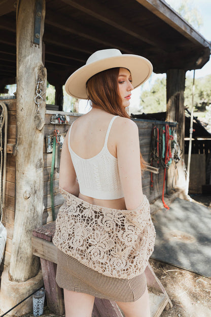 Model wearing a boho cable stitch brami, styled with a lace shawl and wide-brim hat outdoors