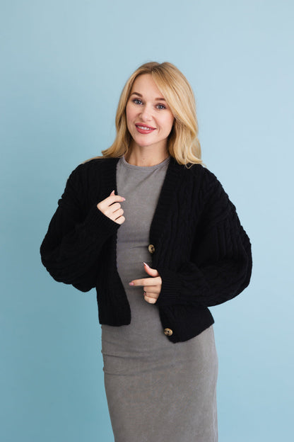 Leto Collection chunky cable knit cropped cardigan in black styled with a fitted dress