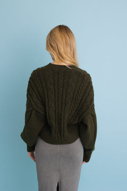 Back view of a Leto Collection chunky cable knit cropped cardigan in olive green with oversized sleeves