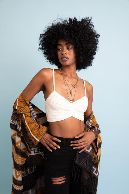 Woman wearing a cozy knit brami top with layered necklaces and a patterned shawl