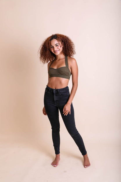 Model wearing Leto Collection boho cross strap bralette with high-waisted black jeans for a trendy look