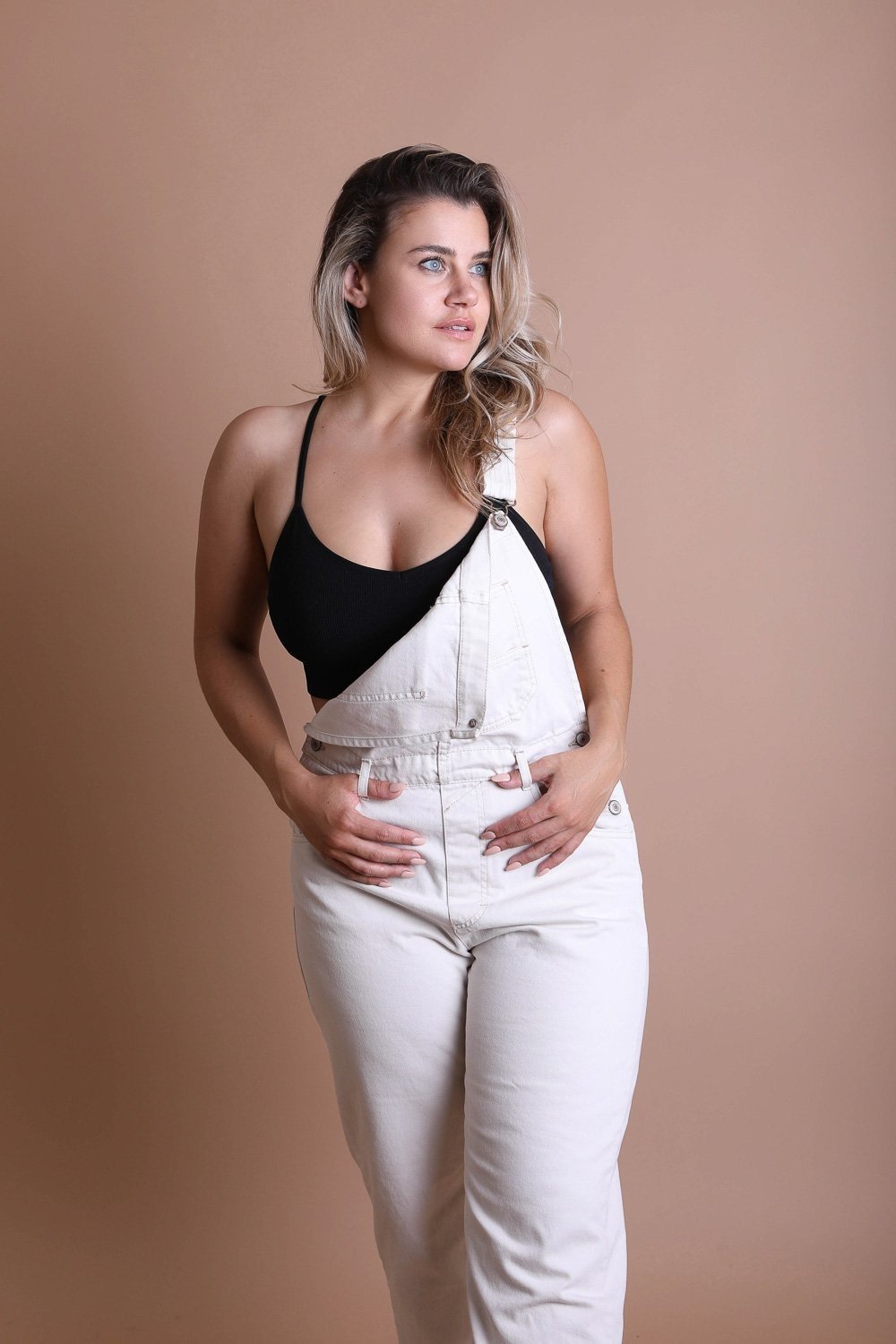 Model wearing plus size dream catcher bralette paired with white overalls for a trendy look