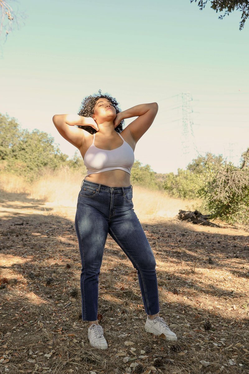 Model wearing a plus size dream catcher bralette paired with high-waisted jeans in a natural outdoor setting