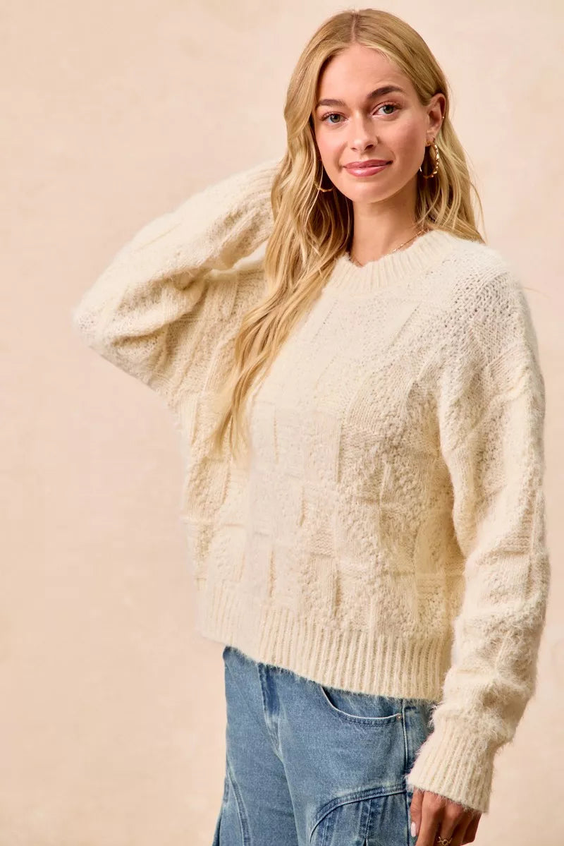 Cream-colored checker board drop shoulder sweater with a relaxed fit and cozy texture