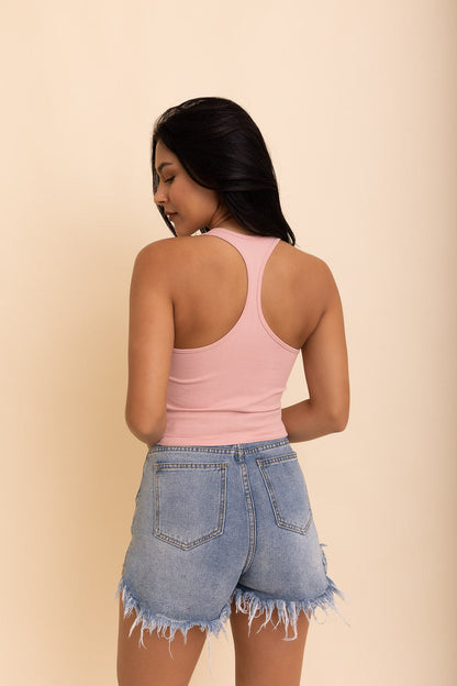 Model wearing a pink boho racerback brami with denim shorts, showcasing a trendy casual look