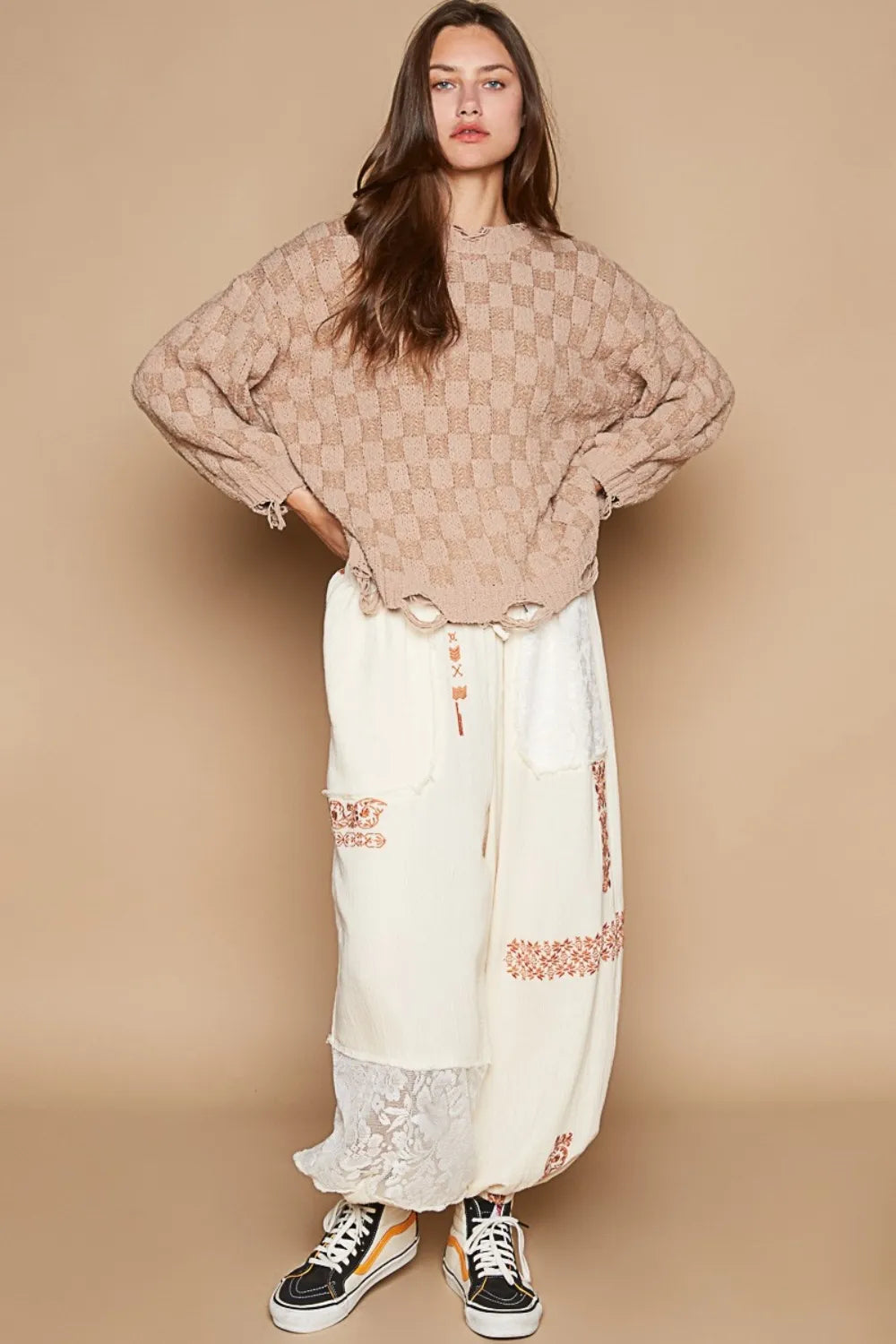 Boho checkered distressed sweater in beige worn with cream wide-leg pants for a relaxed style