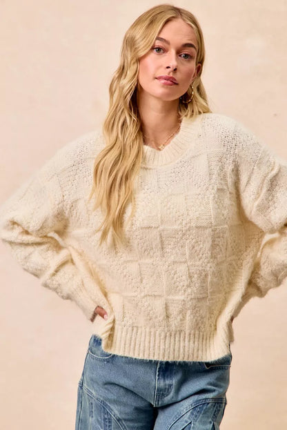 Cream colored checker board drop shoulder sweater featuring a cozy oversized fit