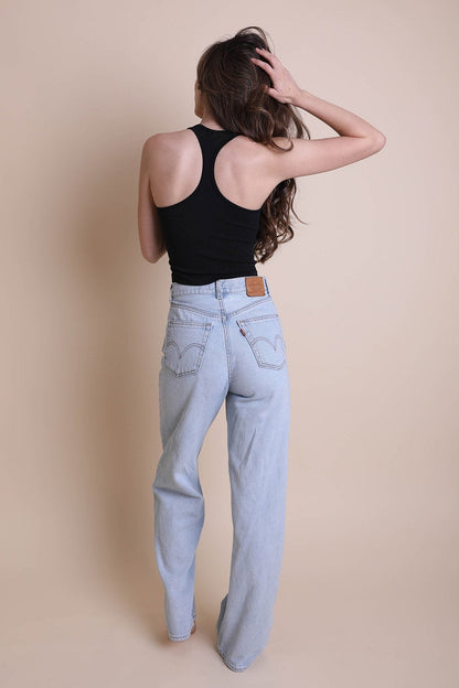 Model wearing a high neck racerback brami in black with light wash jeans from Leto Collection
