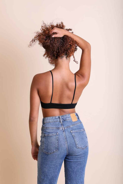 Model wearing a black boho plunge bralette paired with high-waisted jeans from Leto Collection
