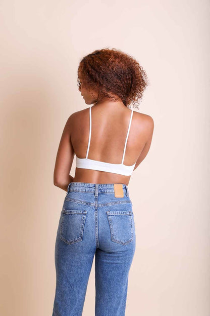 Leto Collection Boho Plunge Bralette in white, featuring a simple back design paired with high-waisted jeans.
