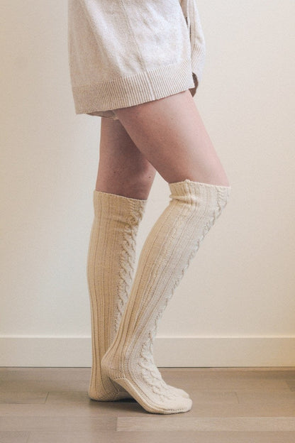 Cream knee high cable knit socks designed for warmth and comfort during colder seasons