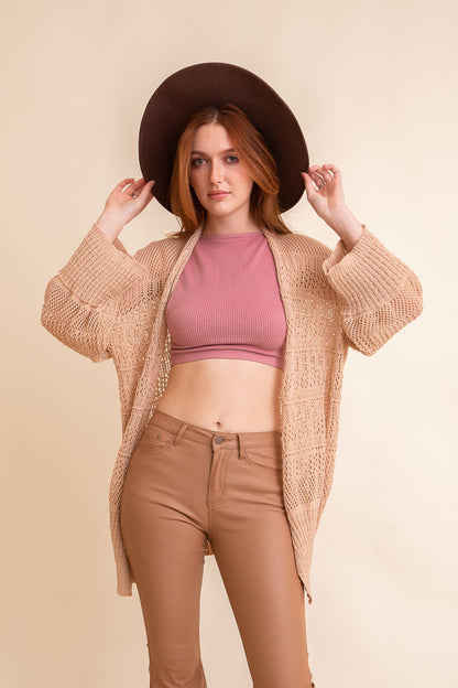 Leto Collection boho knit cardigan in beige worn over a pink crop top with a stylish hat