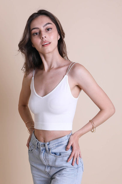 Model wearing a white low back brami top paired with light blue jeans for a stylish look