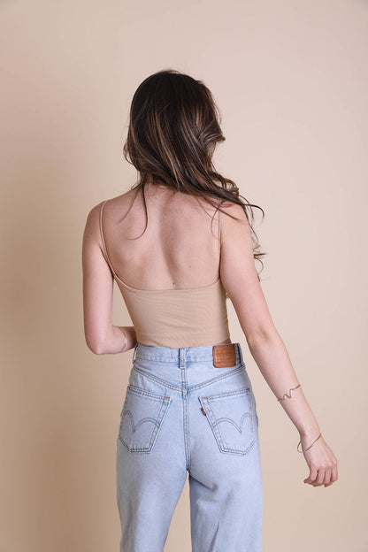 Model wearing a low back brami top in beige with high-waisted jeans, showcasing a stylish back view
